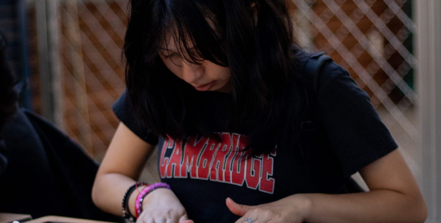 girl wearing cambridge tshirt flattening playdough with a pencil web
